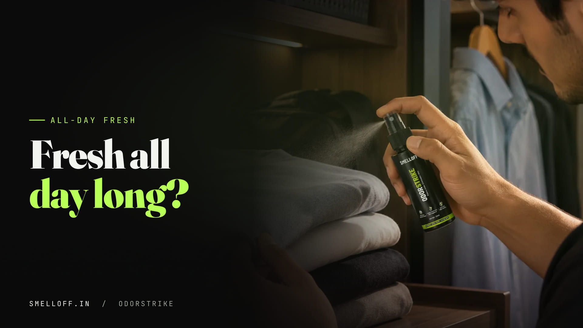 A hand holds the ODORSTRIKE bottle over a stack of folded t-shirts, ready to spray