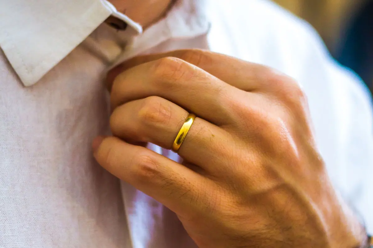 Close-up of a man fastening the top button of a white shirt