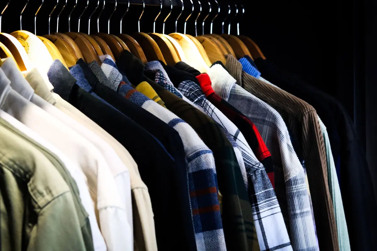 A row of men’s shirts in checks and solids on wooden hangers