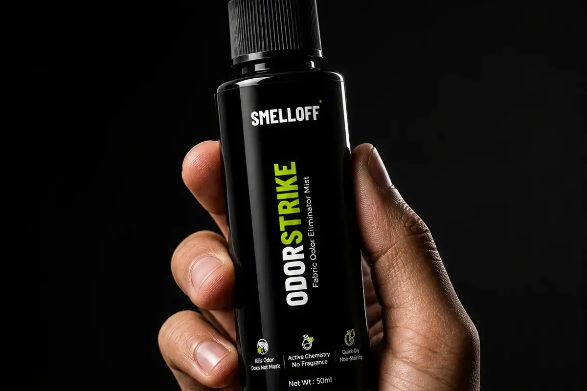 A hand holds the ODORSTRIKE 50ml bottle against a black background