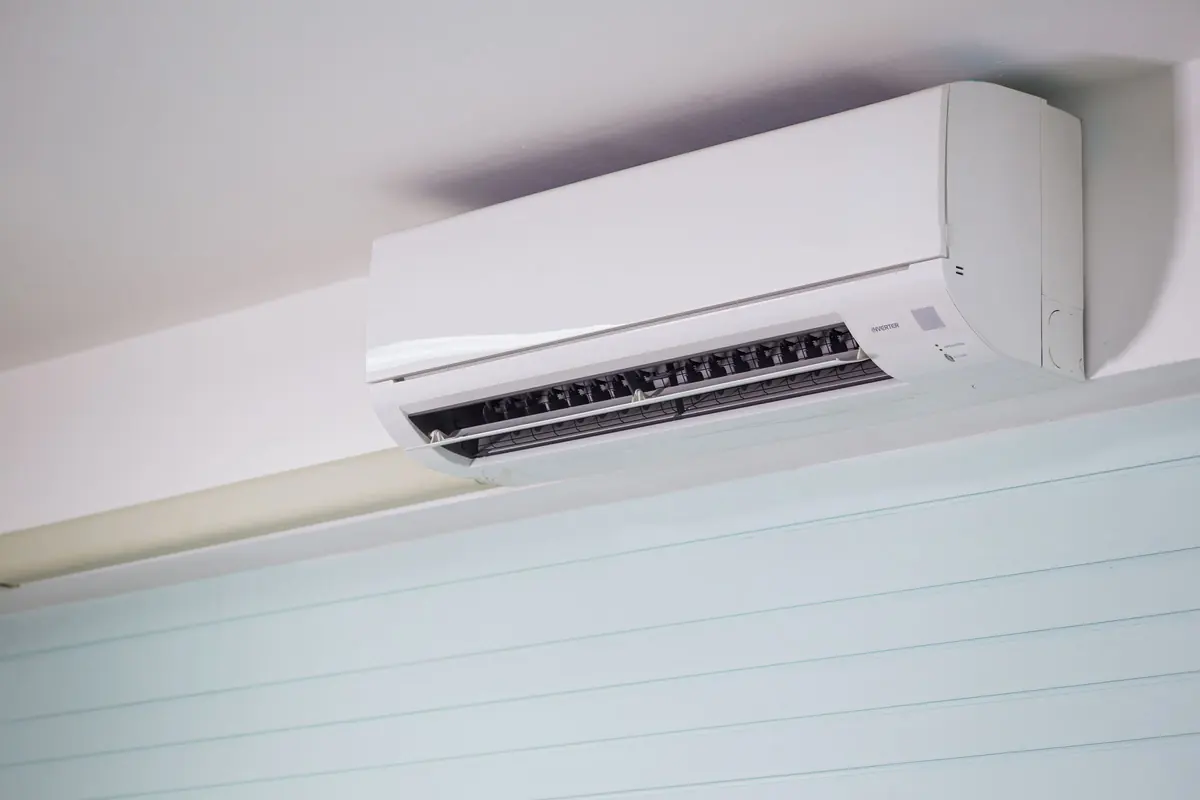 A white wall-mounted split air conditioner high on a pale wall