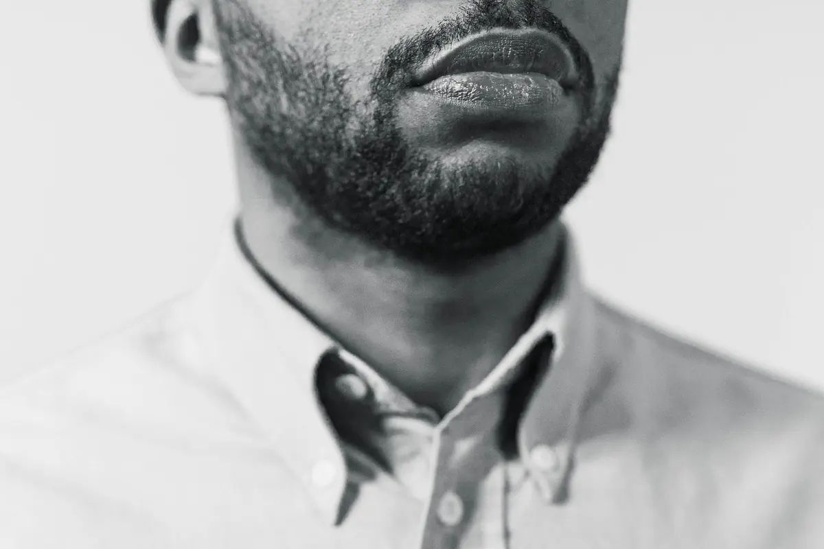 Black-and-white close-up of a man’s open-collar white shirt