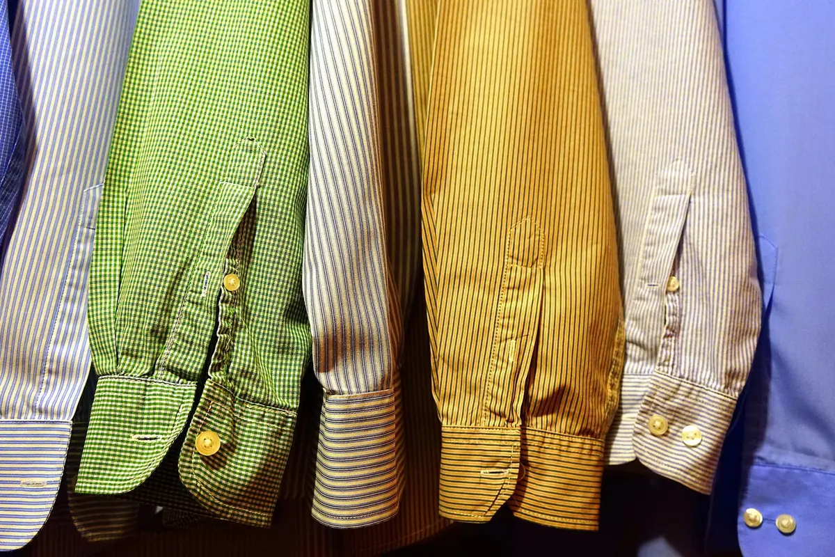 A rail of button-down shirts in blue, green and mustard
