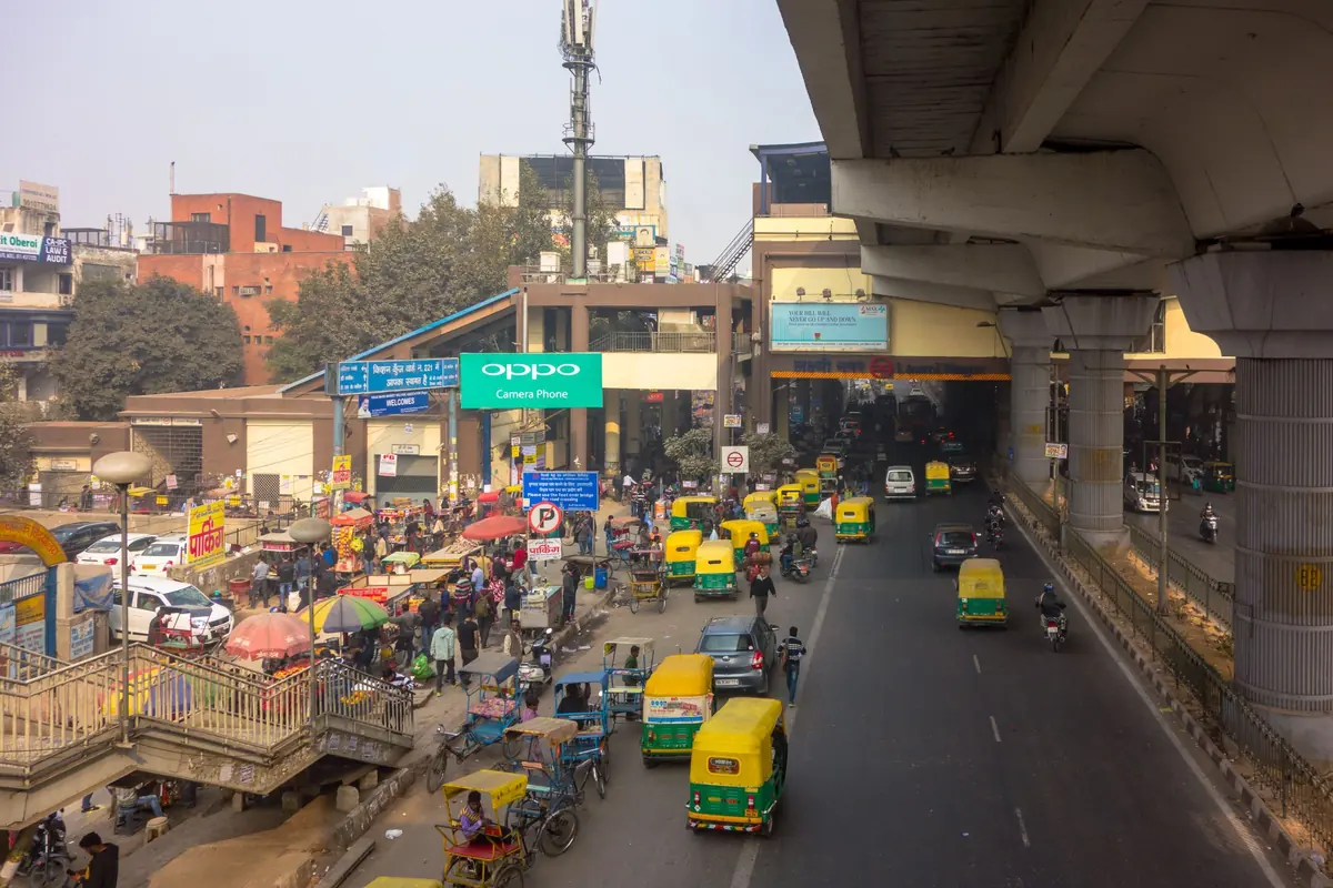 A busy Indian road under a flyover, packed with autos, cars and two-wheelers
