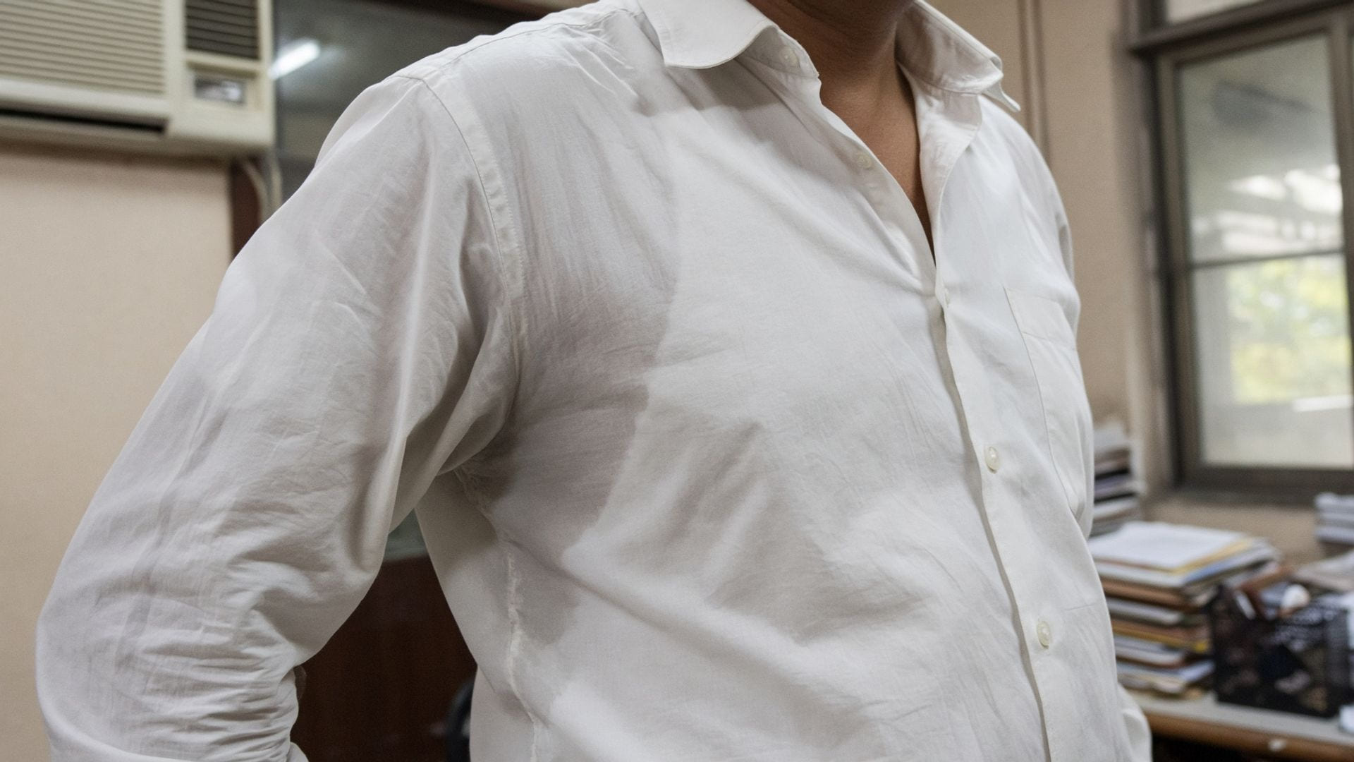 A once-crisp white shirt in a humid Indian office, collar open and the underarm panel darkened after a few hours