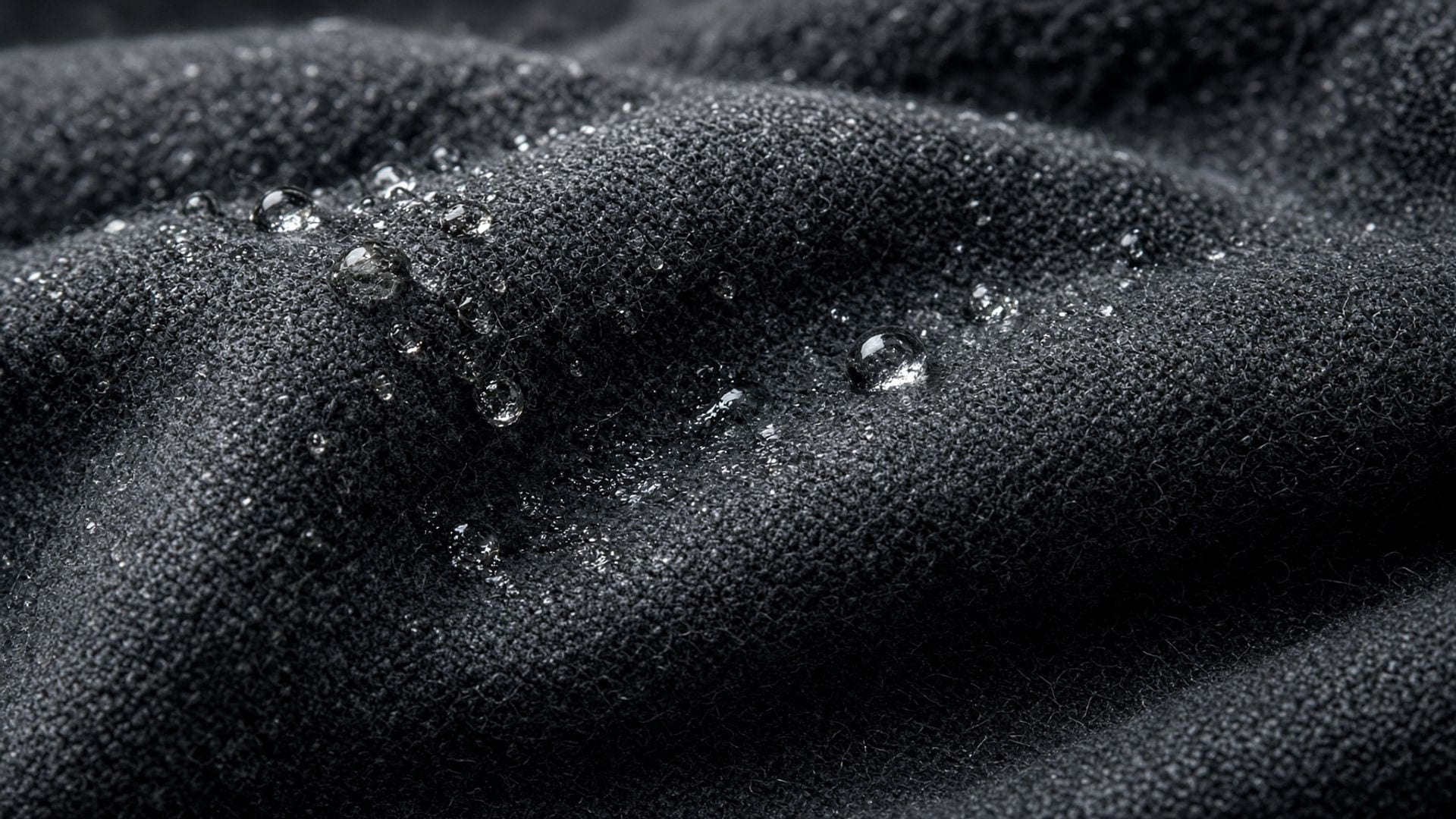 Macro of dark cotton fabric with water droplets soaking into the weave